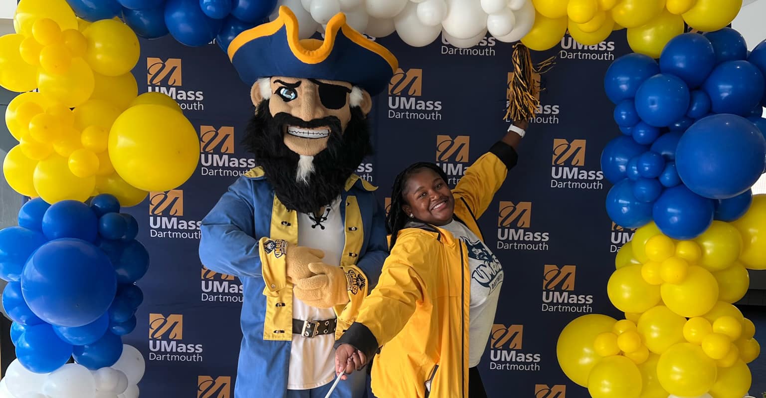 smiling student and campus mascot arnie pose for a photo at our photo wall
